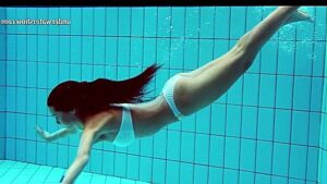 Removes swimsuit underwater and swims naked